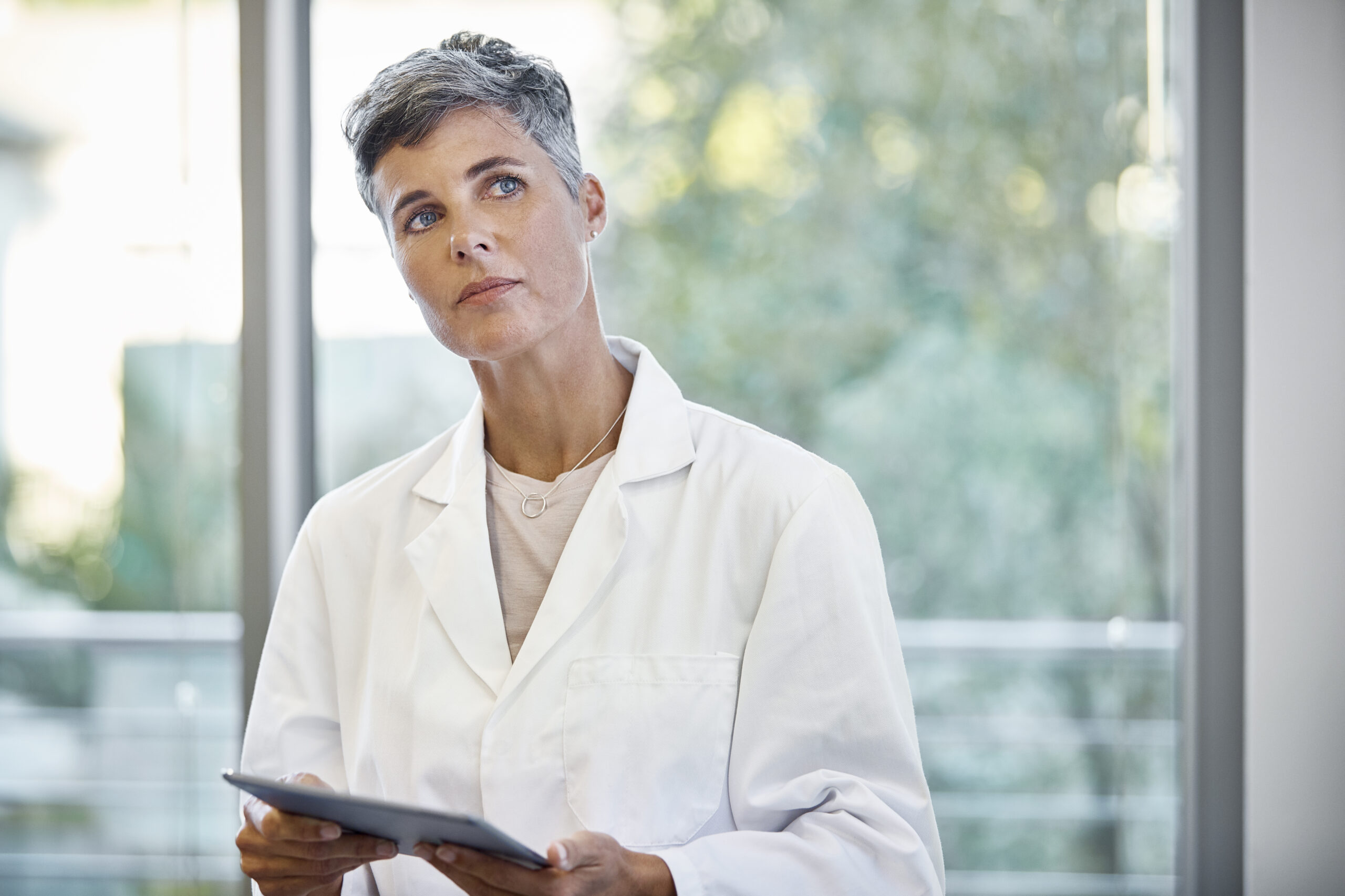 Naislääkäri mietteliäänä tabletti kädessään