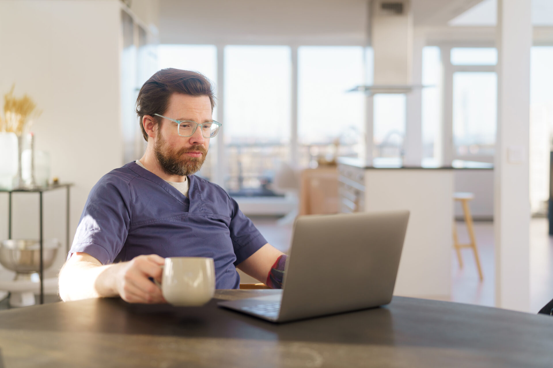 Lääkäri istuu läppärinsä ääressä kotonaan