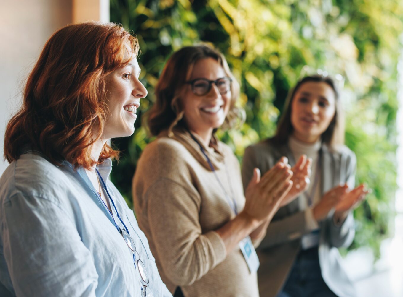 Kolme naista pitää kokousta ja taputtaa.